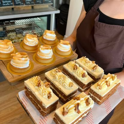 A tray of freshly made lemon meringue tarts and cake slices being carried out to the counter at Lara Patisserie