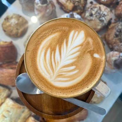A flat white with tulip latte art in front of the pastry counter